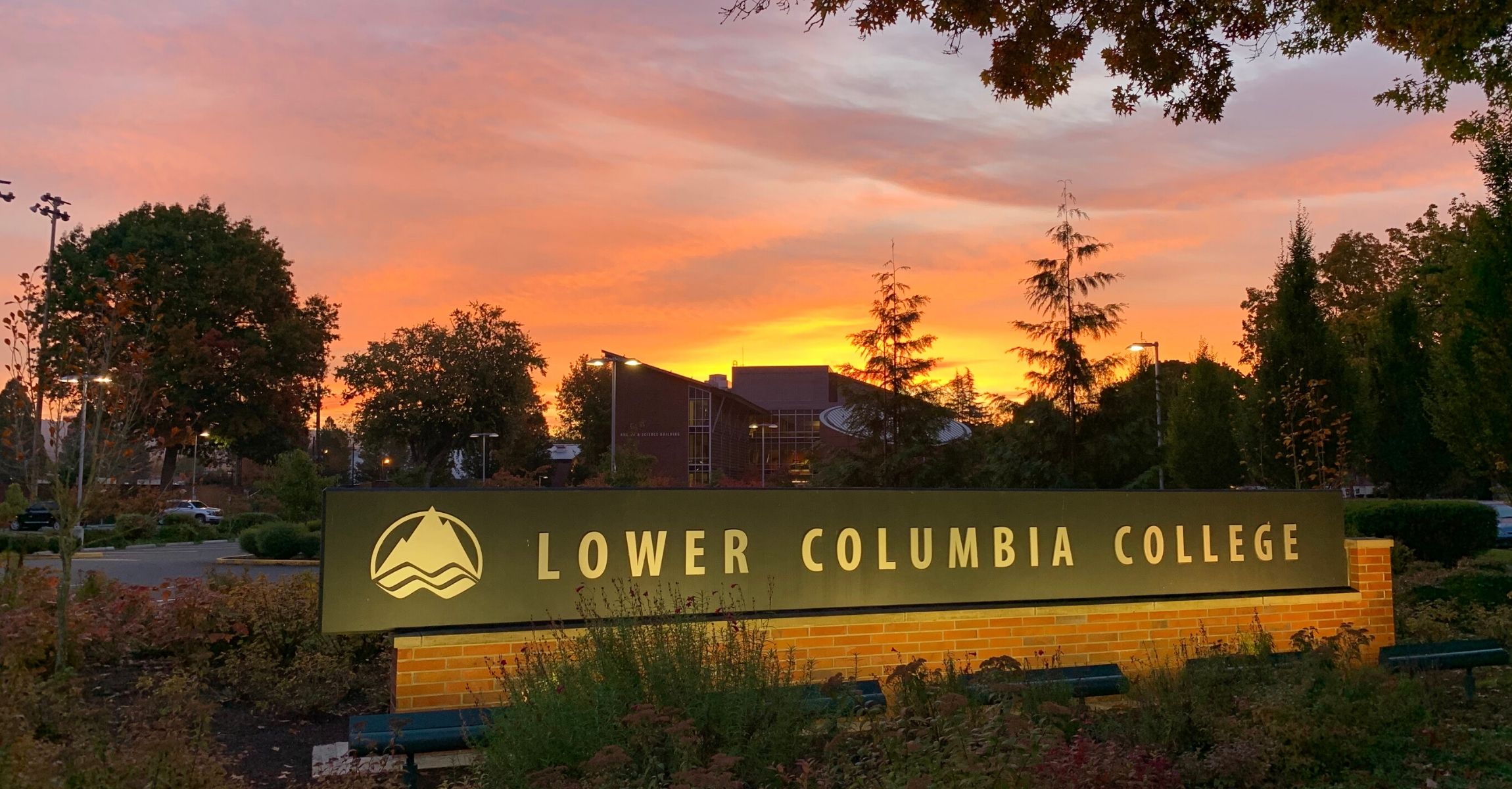 A photo of the Lower Columbia College sign on campus at night with lighting from below the sign.