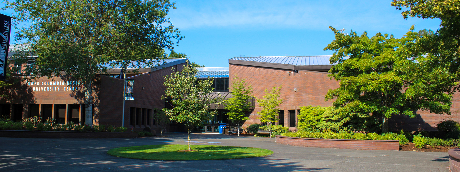Exterior view of the Lower Columbia College Alan Thompson Library and University Center, featuring modern brick architecture and surrounding greenery on a sunny day.