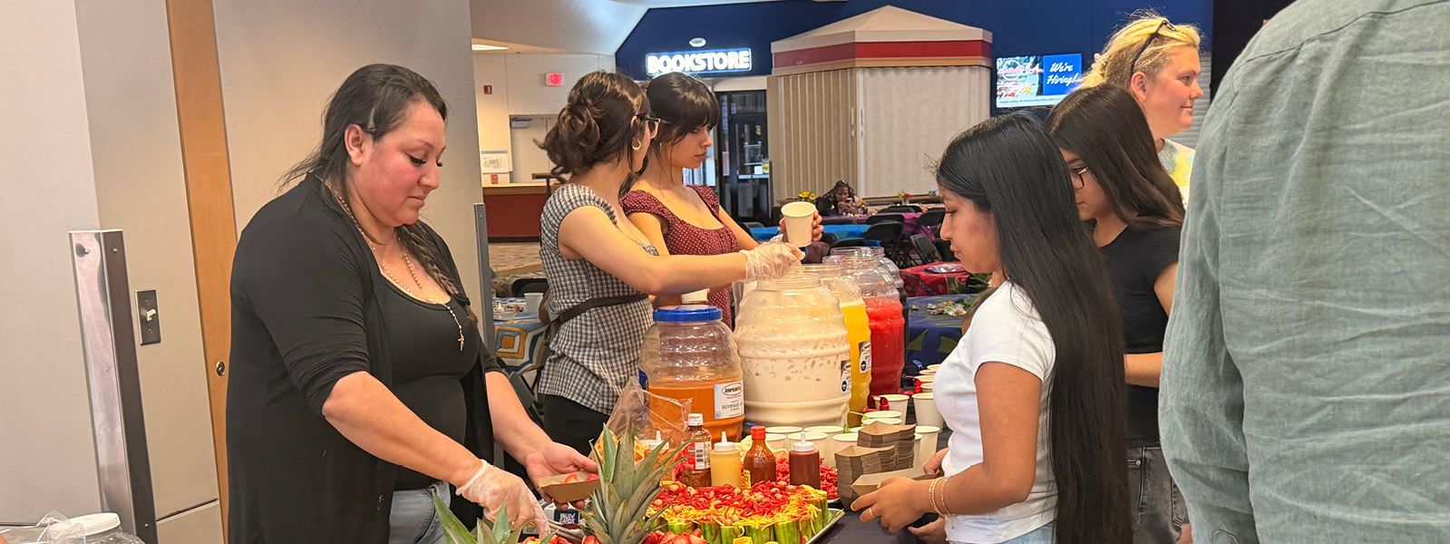 students at a serving table with fruits, finger snacks, and agua frescas