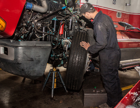 A student in an auto shop working on the engine of a semi truck