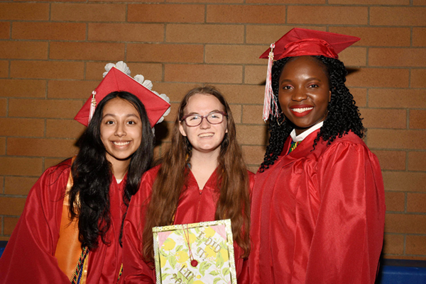 photo of three smiling students in graduation gaps and gowns