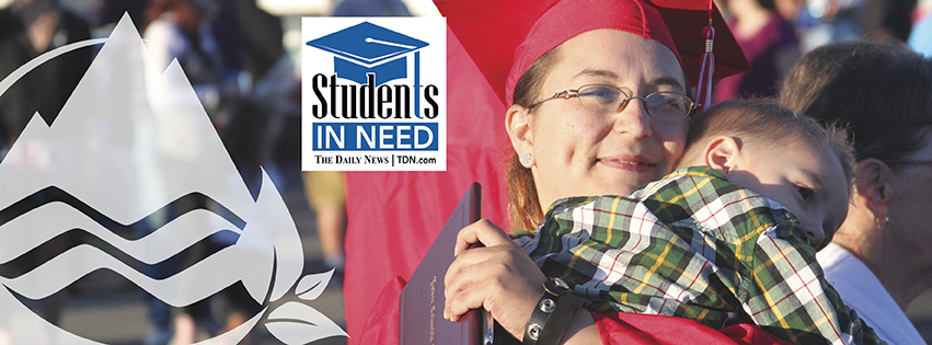 Female student wearing red cap and gown and holding a diploma while hugging a child