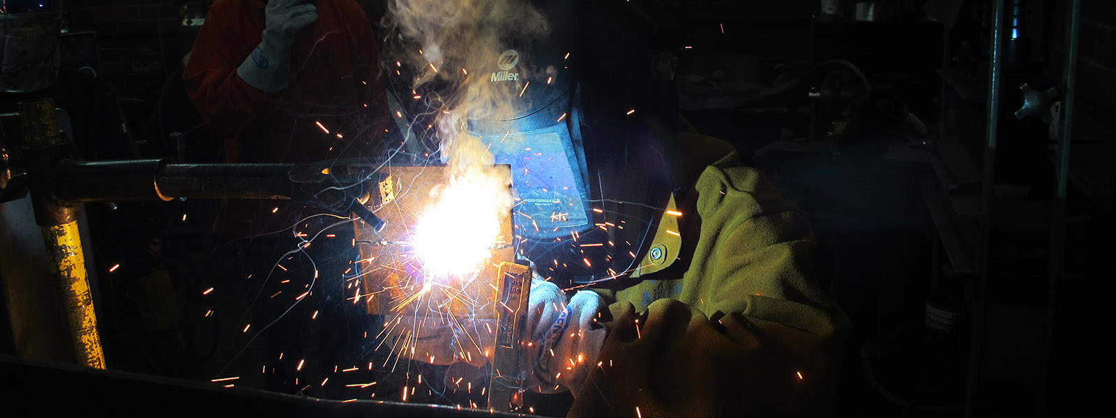 welder with mask on welding and sparks flying