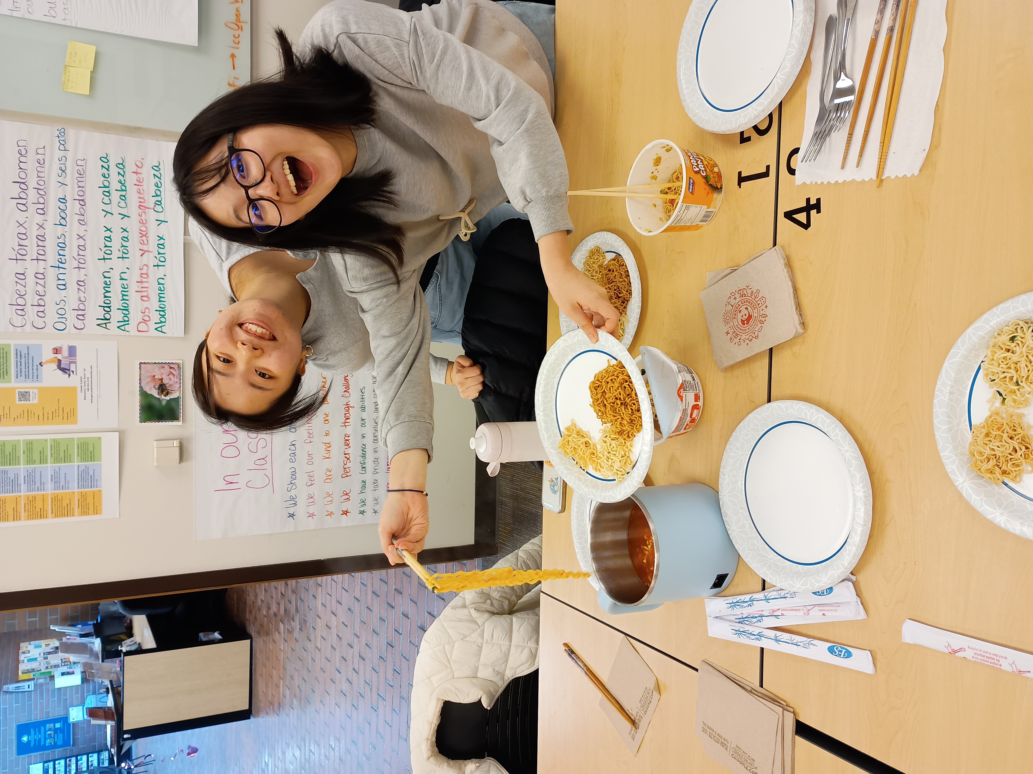 Two international students smiling and showing off their different types of ramen noodles