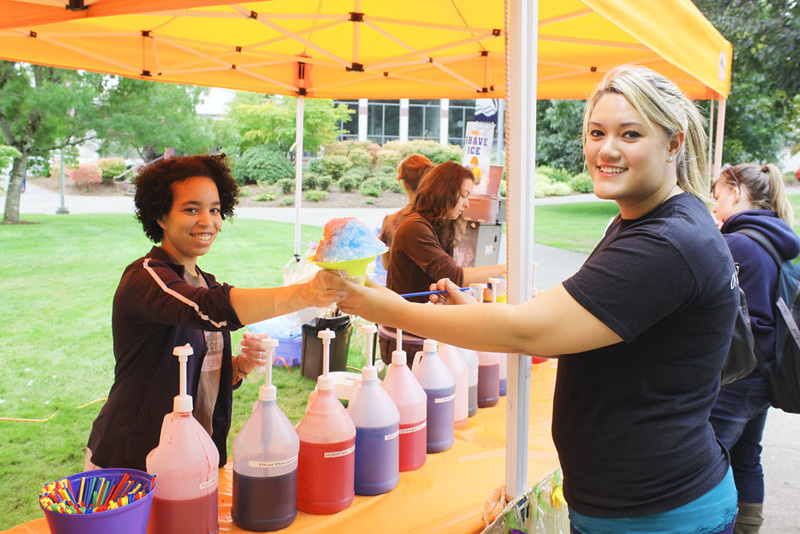 Shaved Ice volunteers serving shaved ice and refreshments from an orange canopy tent at LCC