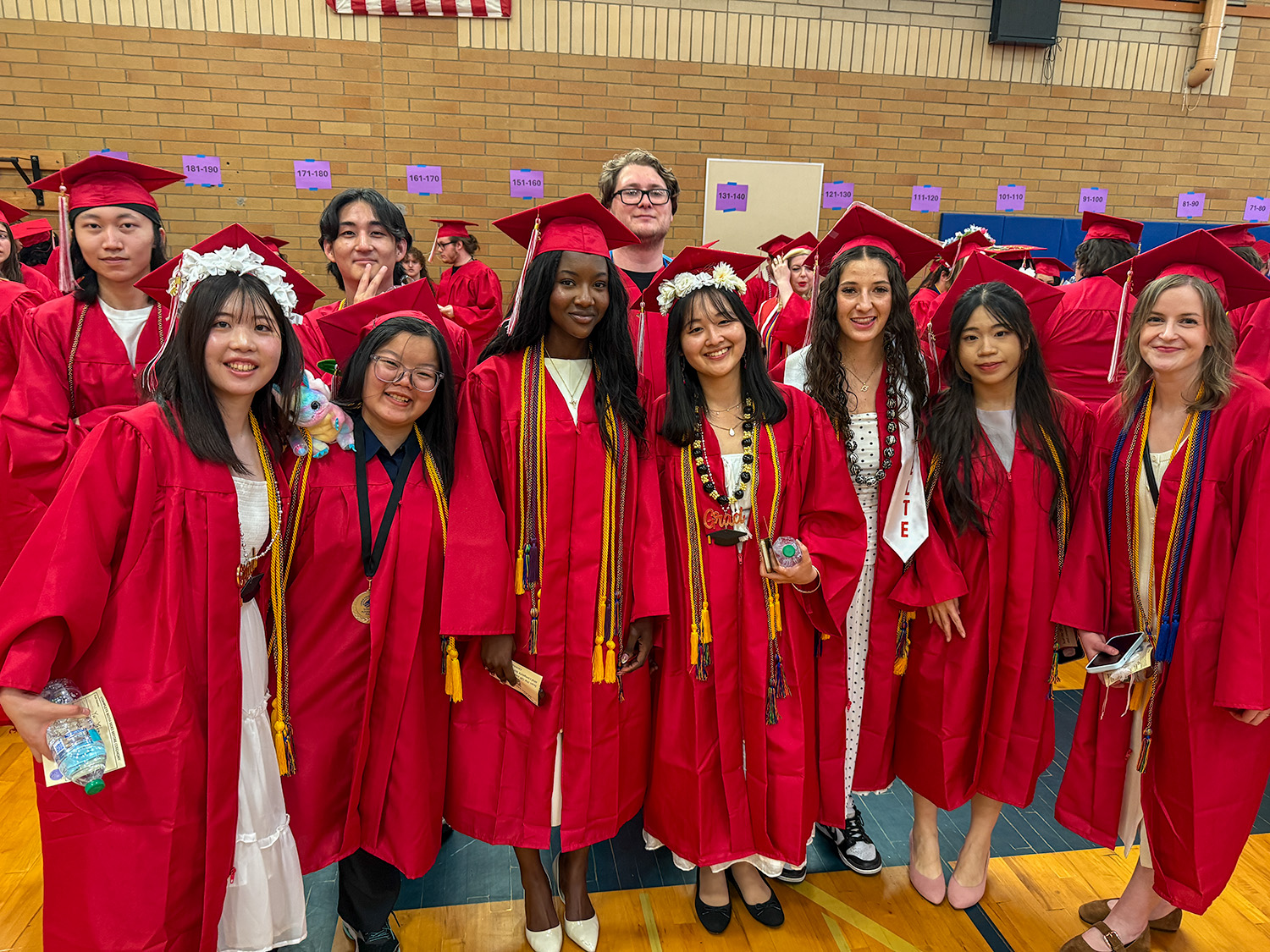 LCC Graduates standing in their red caps and gowns smiling