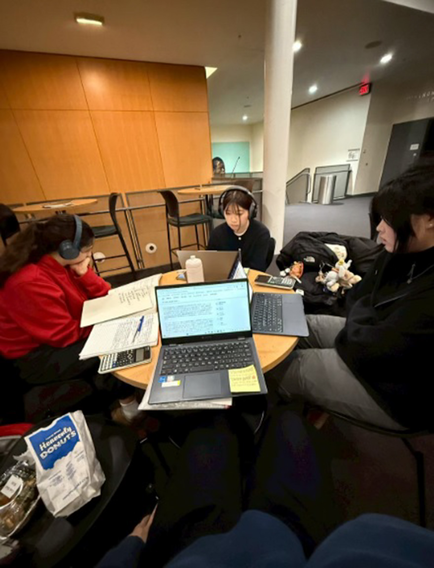 4 International students studying around a round table with laptops and textbook out infront of them.