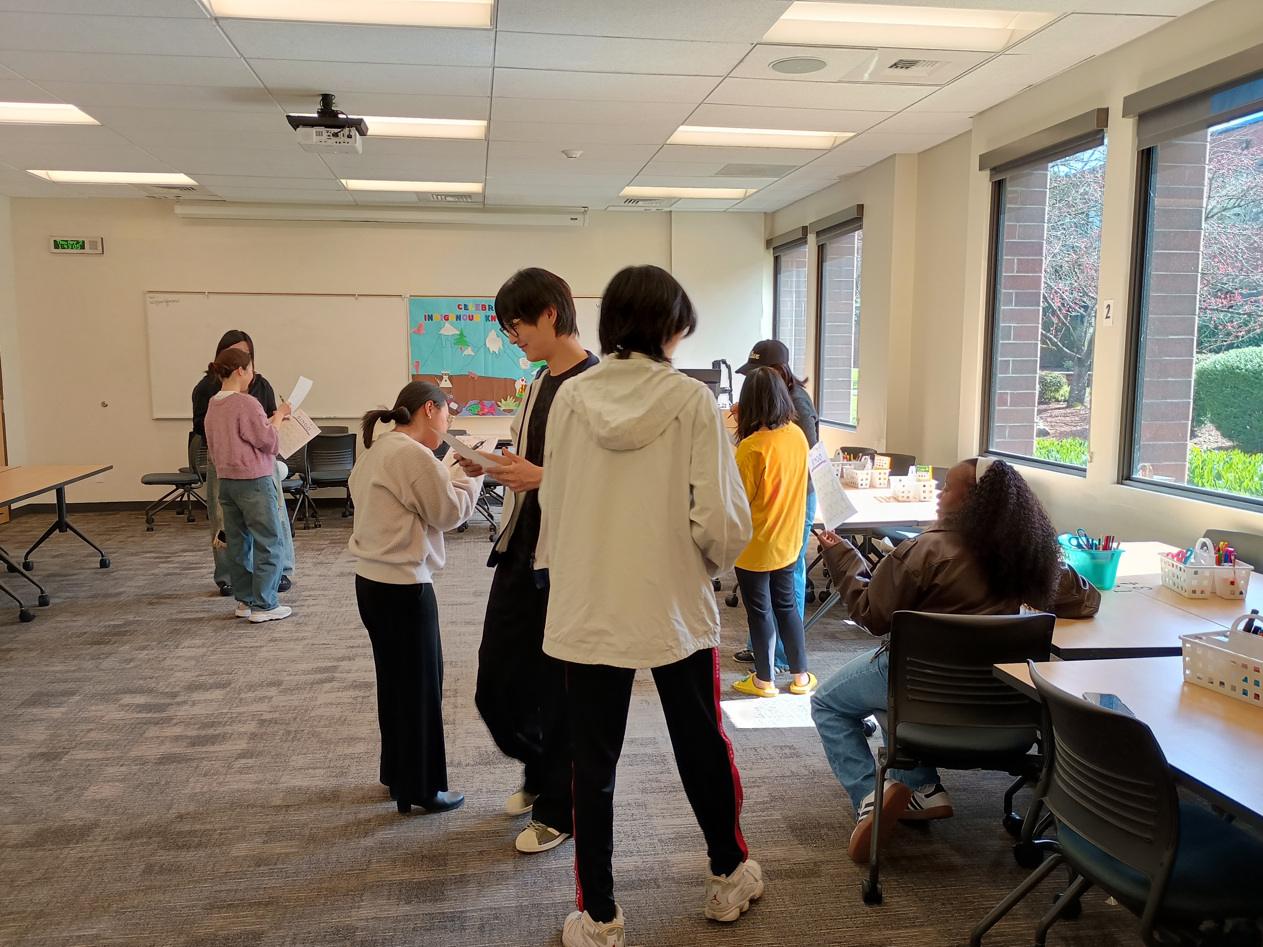 International students walking around a classroom filling out bingo card for an icebreaker activity
