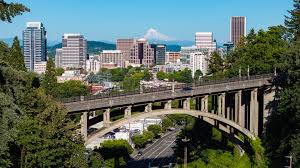 City of Portland walking bridge and scenic view on a sunny day with building and mountains in the background. 