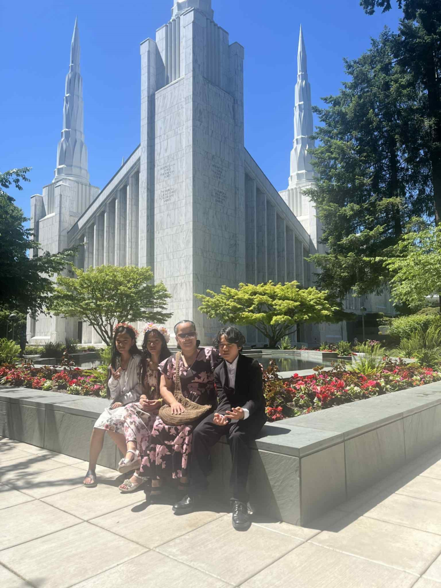 Connie and her three children posing for an image with the Mormon Temple behind them on a clear blue sky