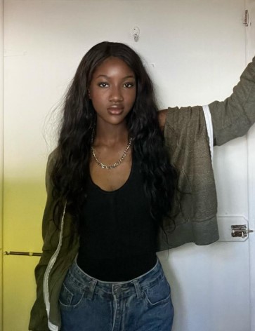 Student ambassador, Covenant, profile image posing in front of a white door wearing blue jeans, black shirt and a grey zip up jacket