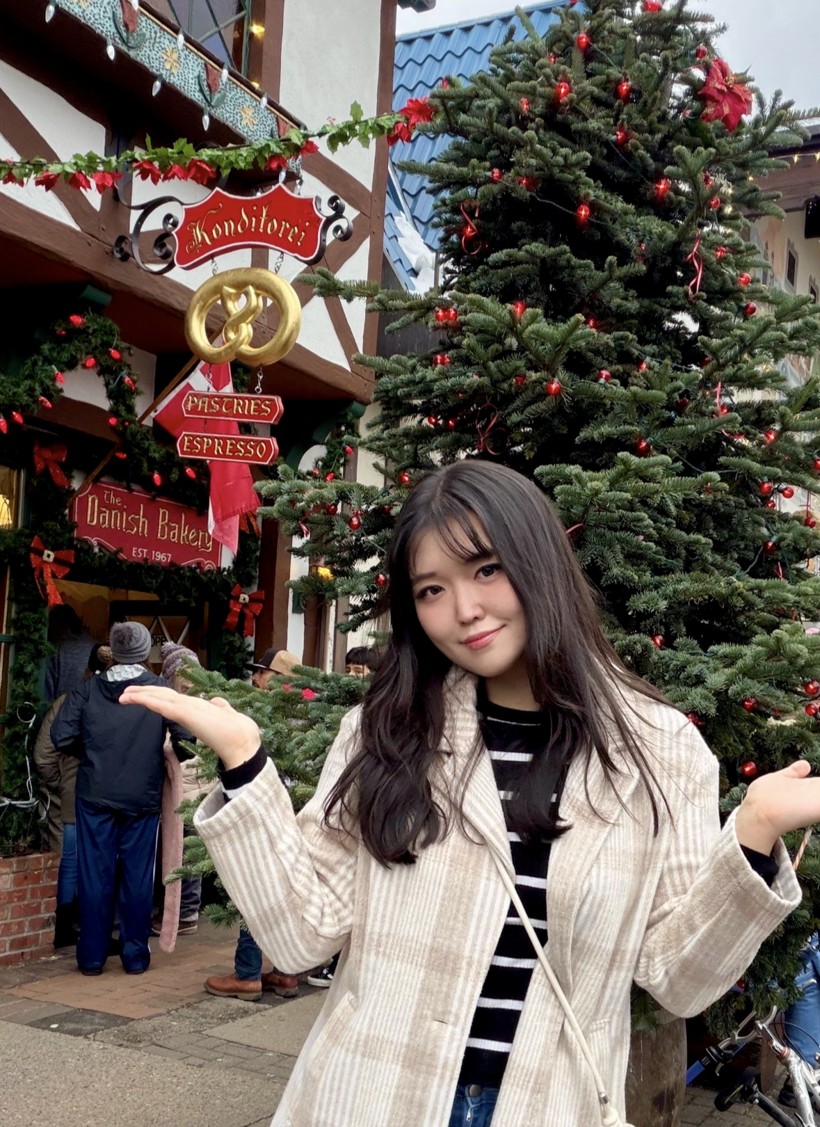 Female foreign exchange student posing in front of a Christmas tree and holiday store