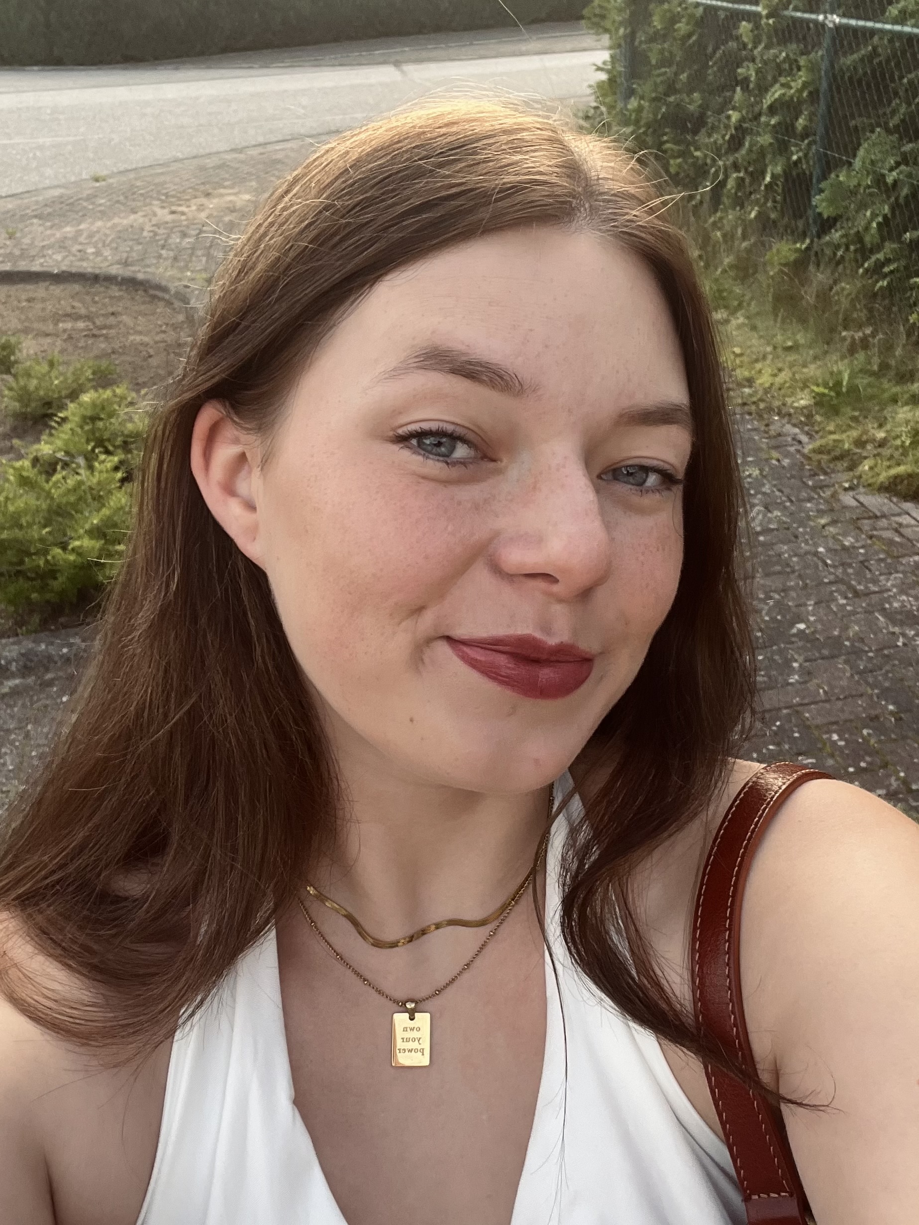 Celina headshot image wearing a white shirt on a sunny day