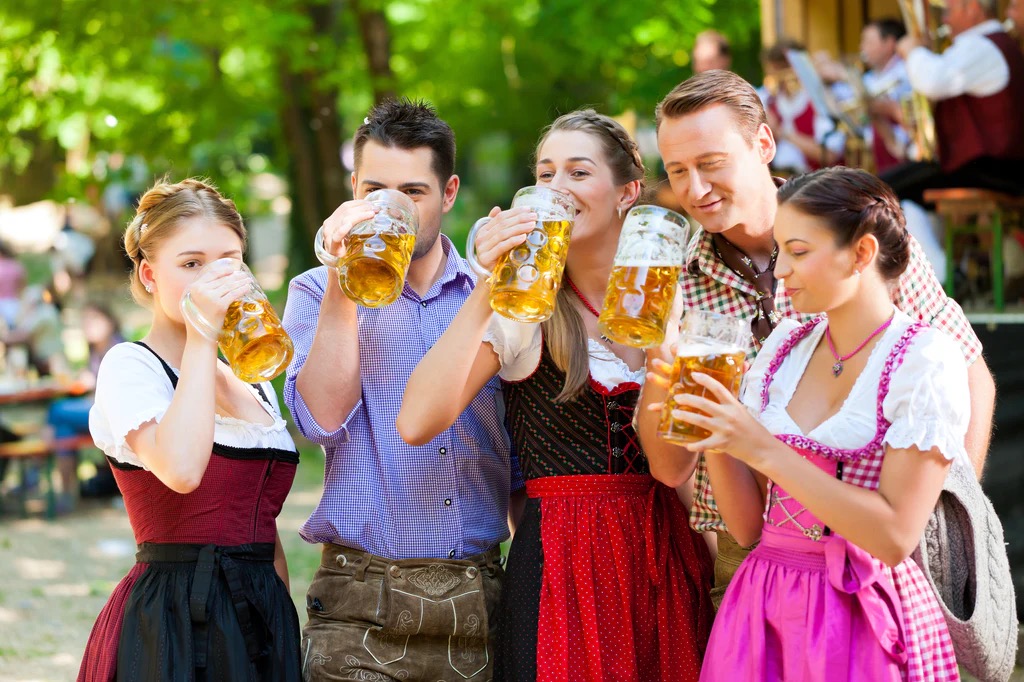 Oktoberfest in Bavaria, where people wear traditional clothing, „Lederhosen“ for men and „Dirndls“ for women, and enjoy German beer, music, and regional food like „Weißwurst“ (Bavarian veal sausage) and „Brezen“ (large soft pretzels).