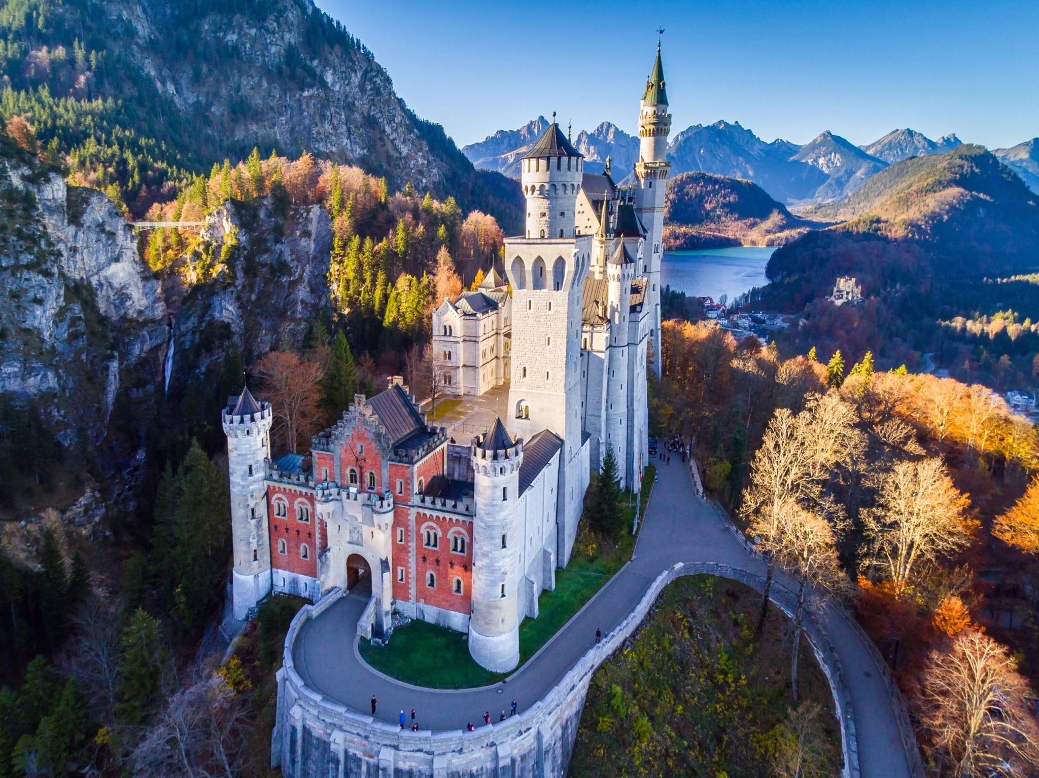 Castle in Germany located in the hills with blue skies, clear rolling hills, a rive, and a brick castle like building in the middle