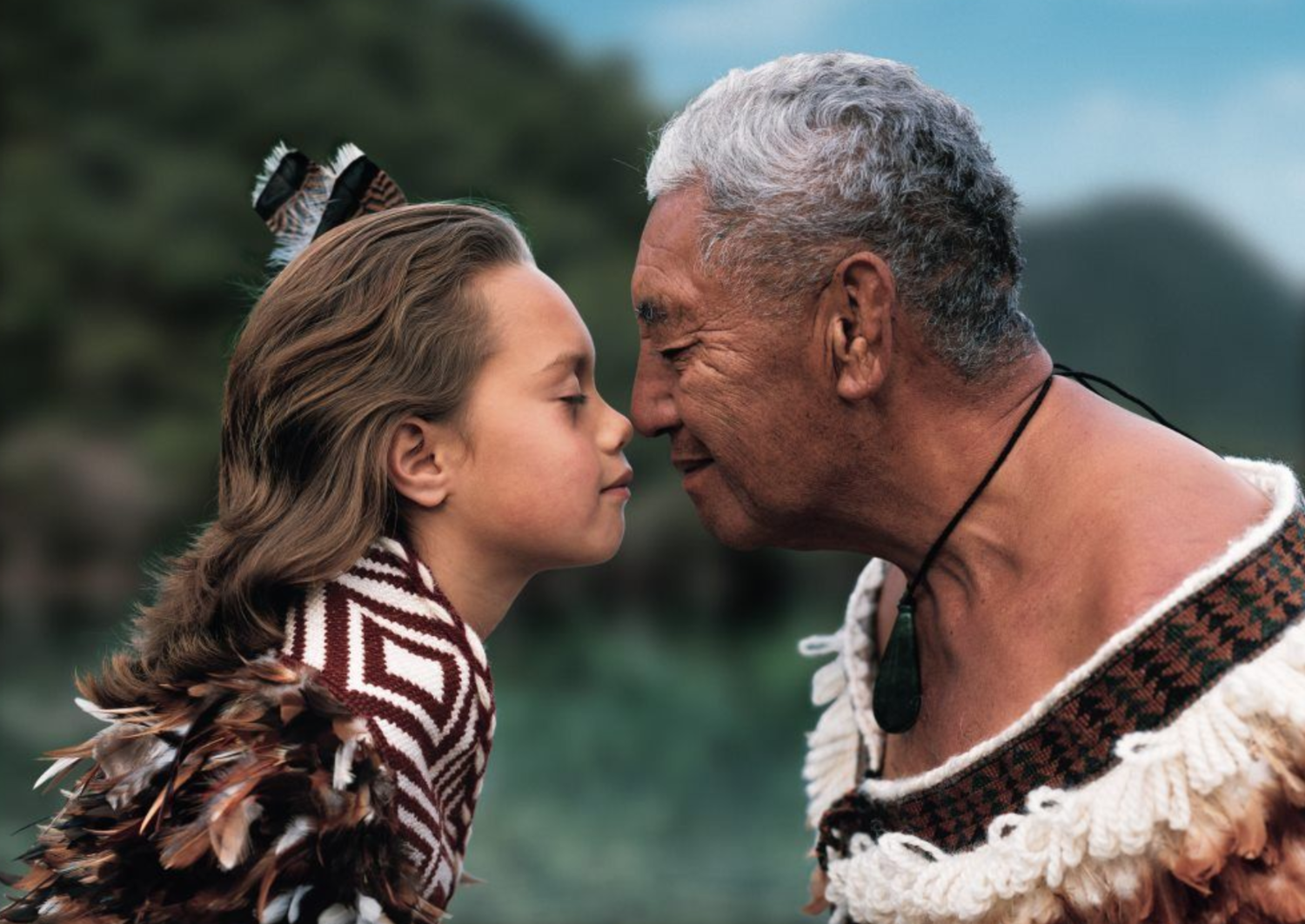 international signs of welcome and greeting. An elder greeting a youth facing one another with noses touching and eyes closed.