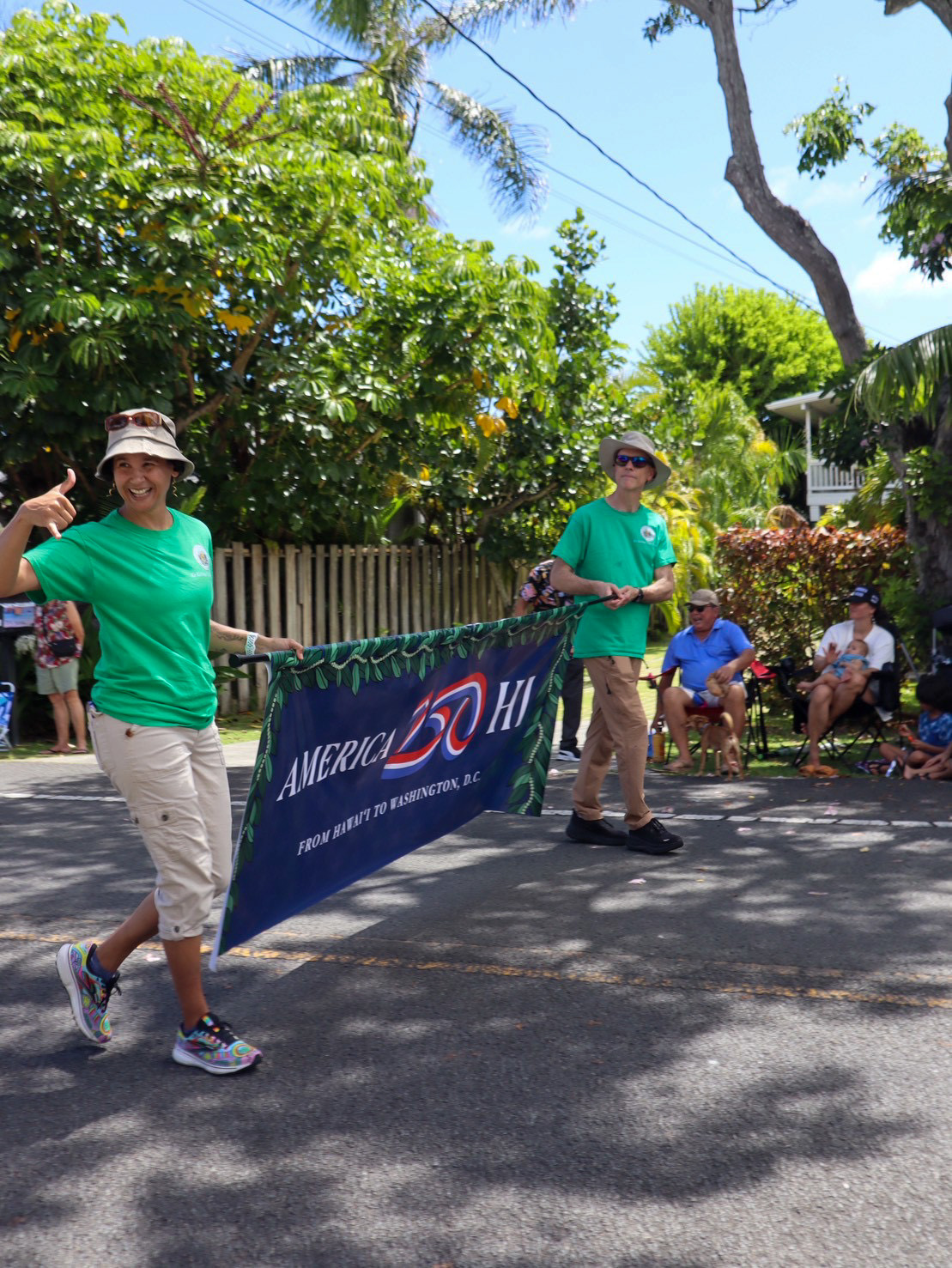 Hawaii-Parade 2 2 people carrying a banner that says "America 250, From Hawai'i to Washington, D.C."