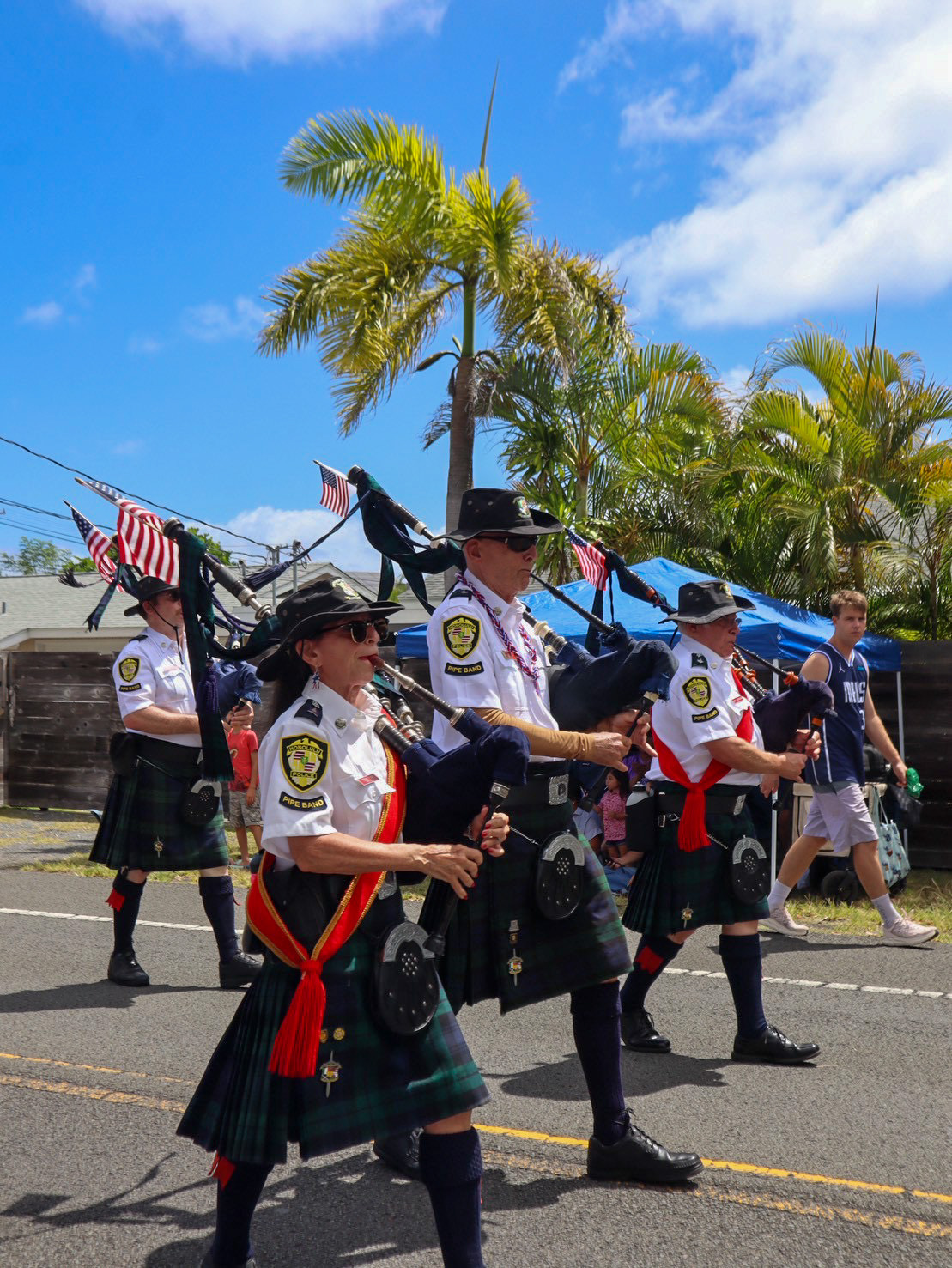 Hawaii-Parade 3 4 members of the Honolulu police pipe band wearing kilts and playing bagpipes as they walk in the parade