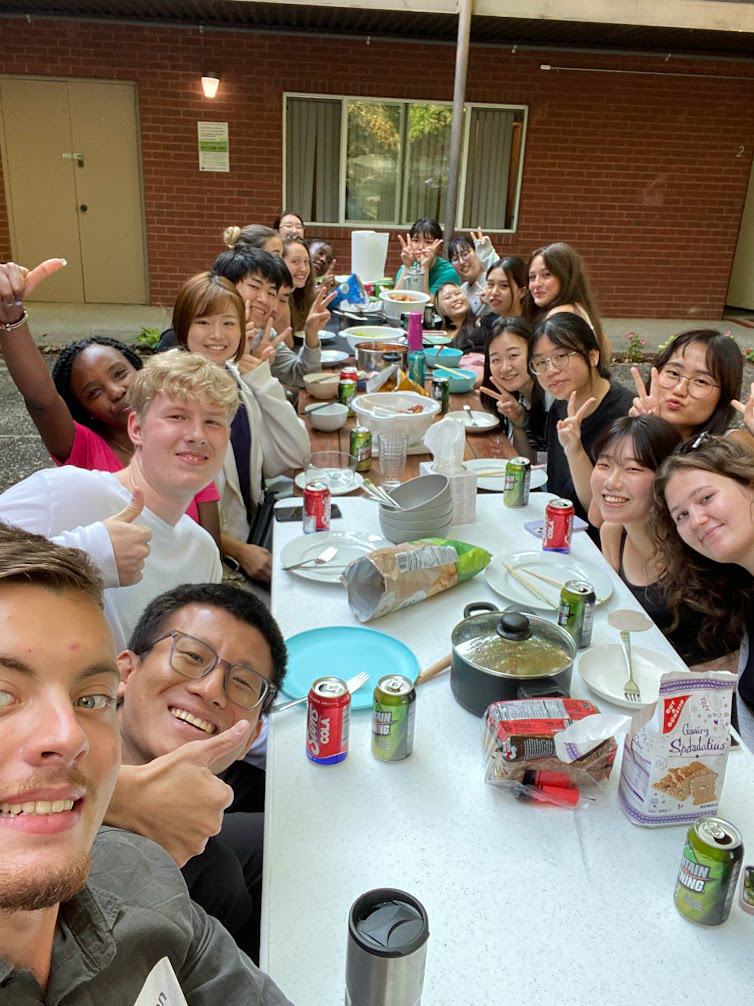 Housing Potluck Students who live in campus Housing sitting around a long table and enjoying a potluck