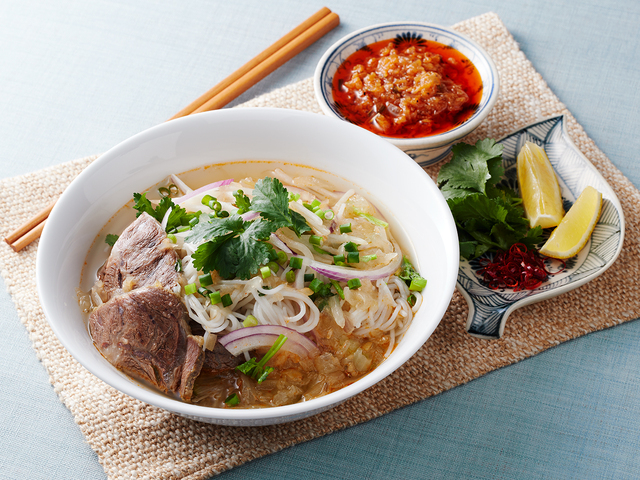 Japanese meal of noodles, vegetables, and soup on a placemat with chopsticks