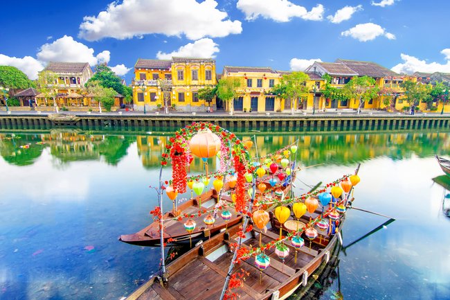 Japanese tourest boats sitting on the river with blue skies and yellow buildings in the background
