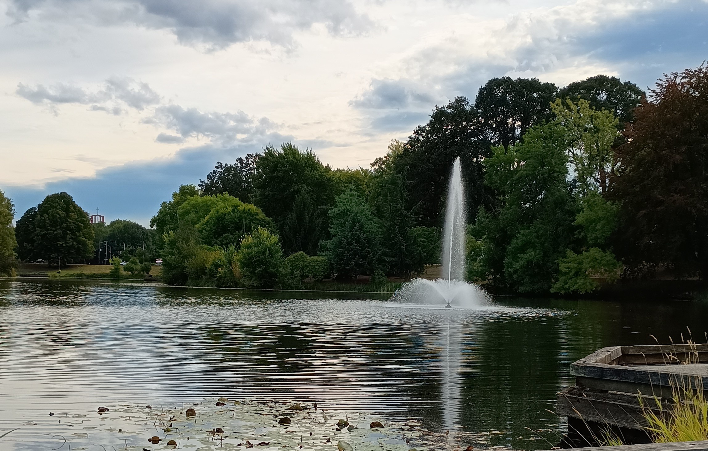 Lake Sacagewea in Longivew washington at the fountains with a cloudy blue sky and full green trees in the backgfound.