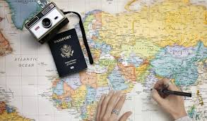 world map with a camera and passport sitting onit and a persons hands with a pencil marking points on the map