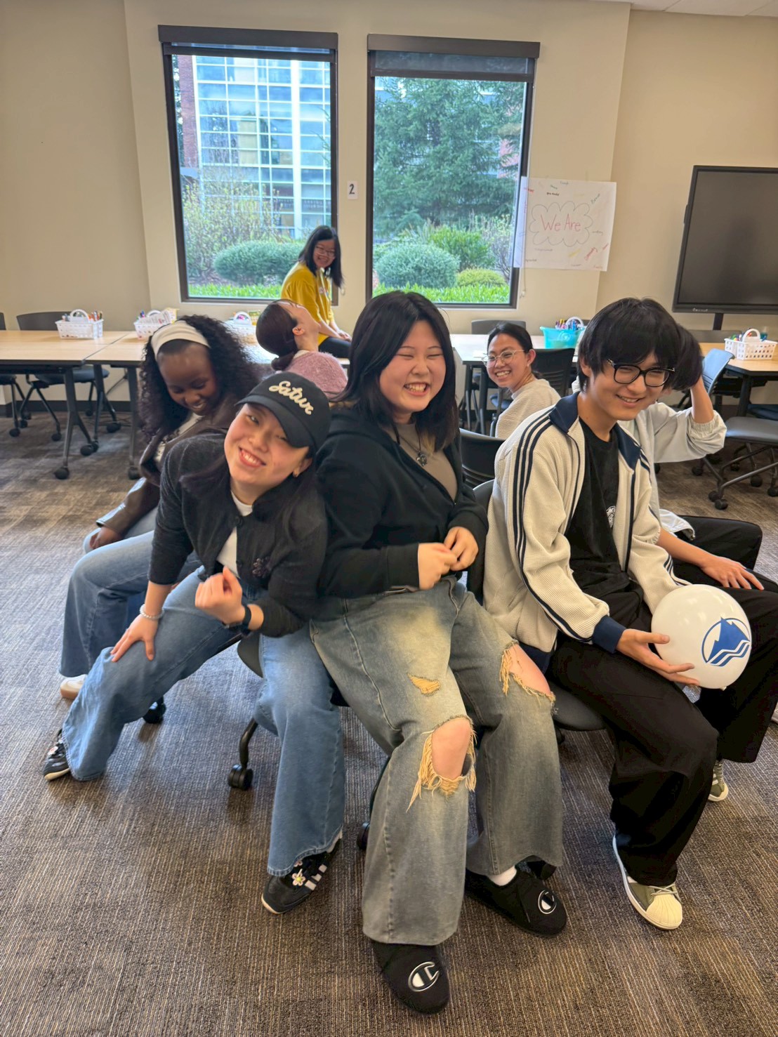 International students in a circle pushing to each get a chair for a game of musical chairs