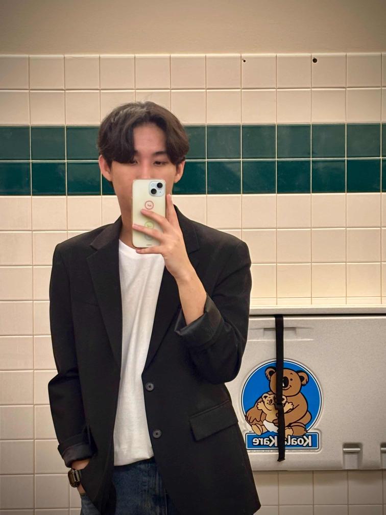 Selfie image of Jin, taken in a room with tile walls in the mirror.