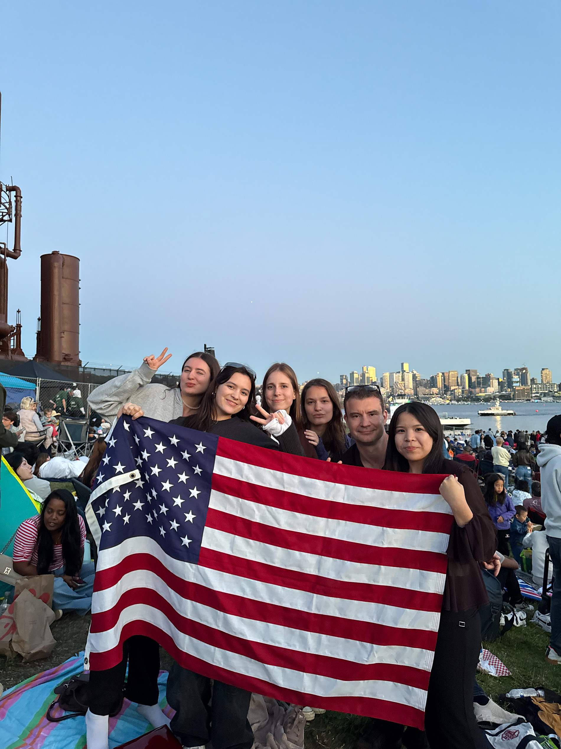 Seattle-Ania with friends at the lake 6 people standing holding an American flag in a large crowd of people
