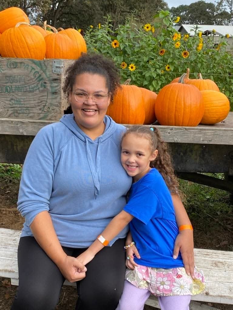 Tashauna and her daughter posing for a picture next to a pumpkin