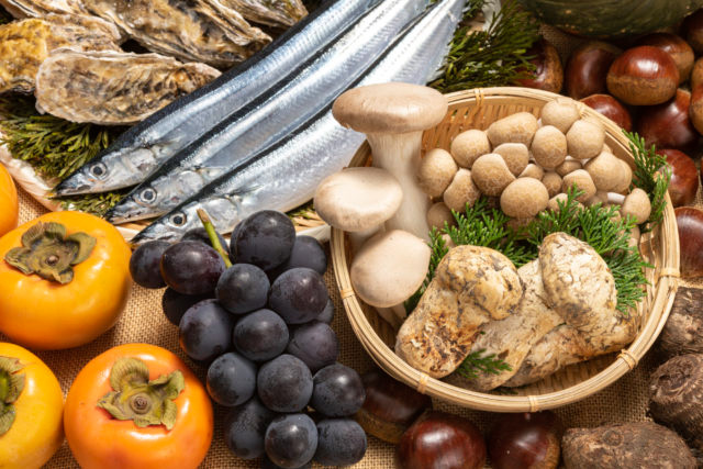 The Autumn of Good Food a close up shot of a table of food with fish, mushrooms, persimmons, grapes, and chestnuts
