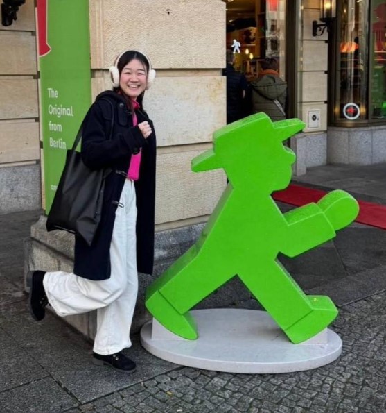 Yuna, international student from Japan, posing next to a freen walking figure.