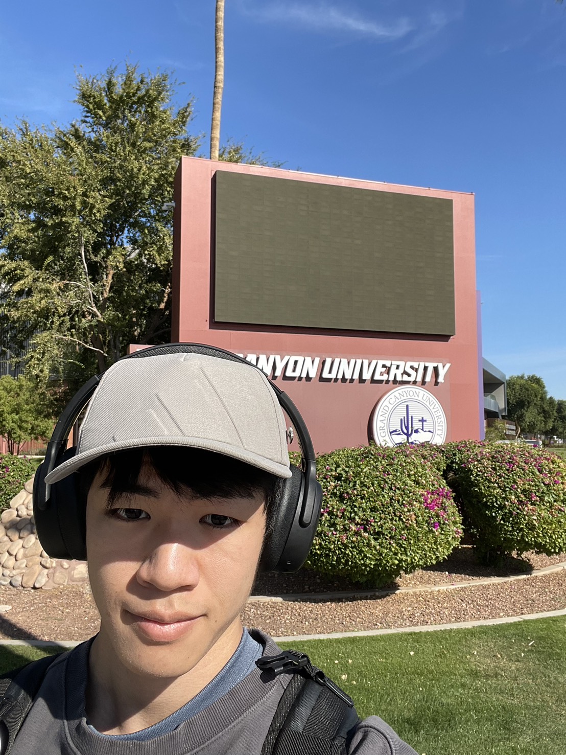 student wearing headphones taking a selfie in front of a GCU