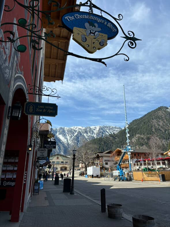 Streets of Leavenworth, mountains and blue skies in the background with a mouse and cheese shop sign hanging from one of the stores.