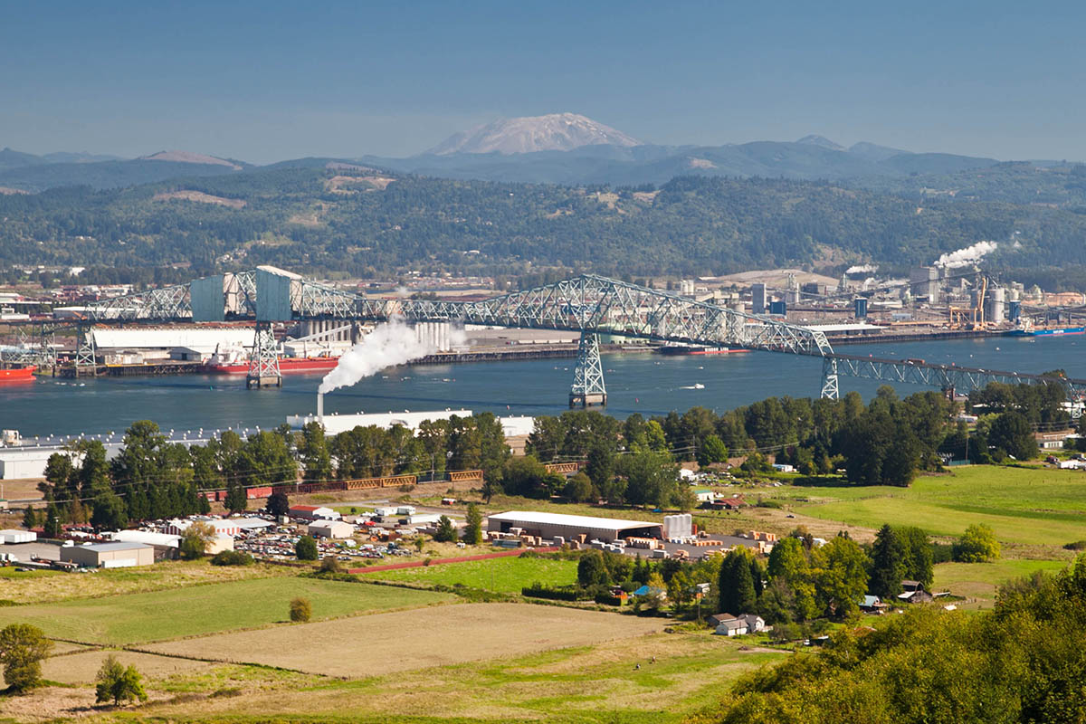 Columbia River and Rainier bridge from an arial view. Housing and businesses on both sides of the river with a bridge crossing over the river and boats in the river and landing at the ports.