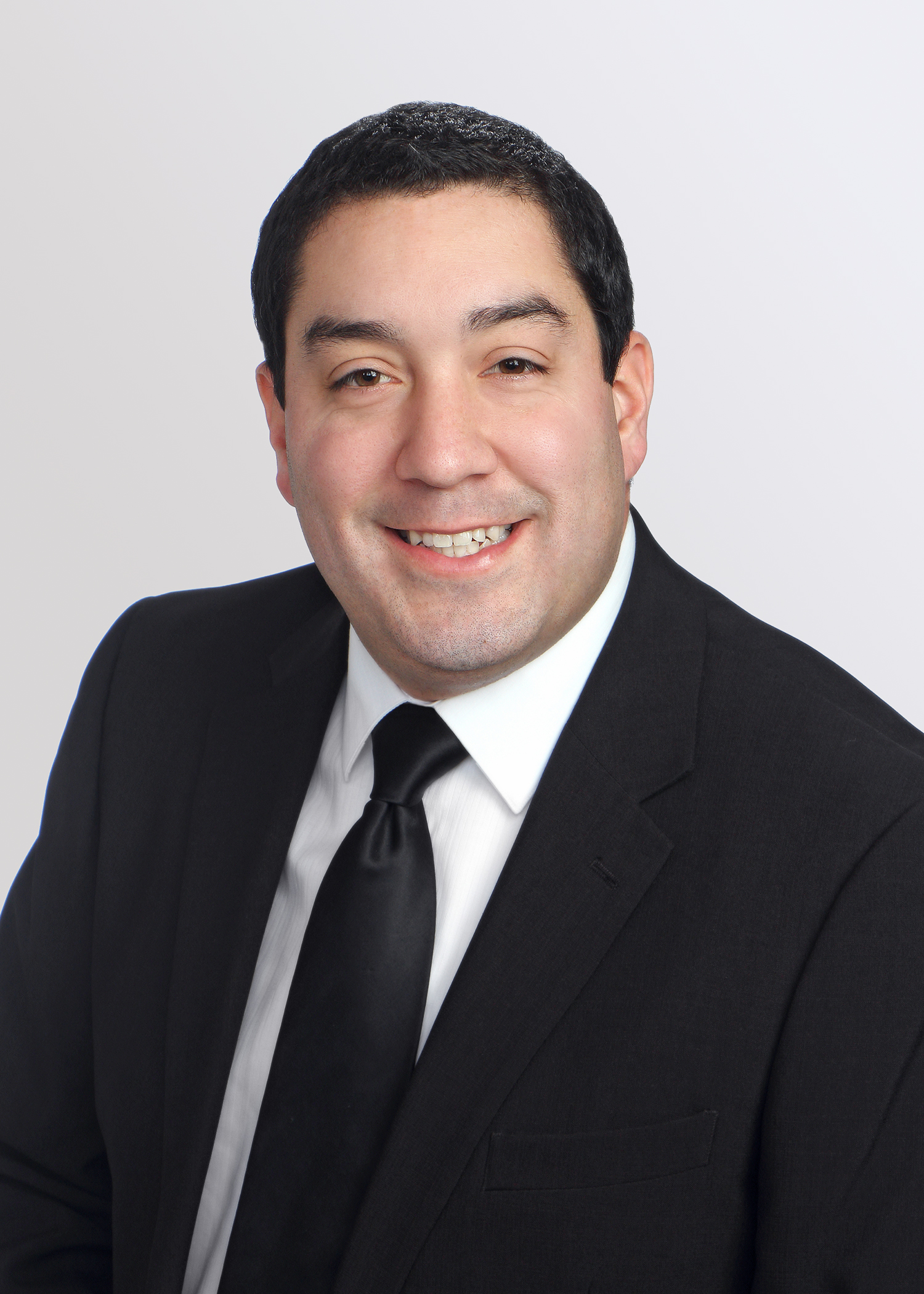 Headshot photo of Marc Silva in a black suit.