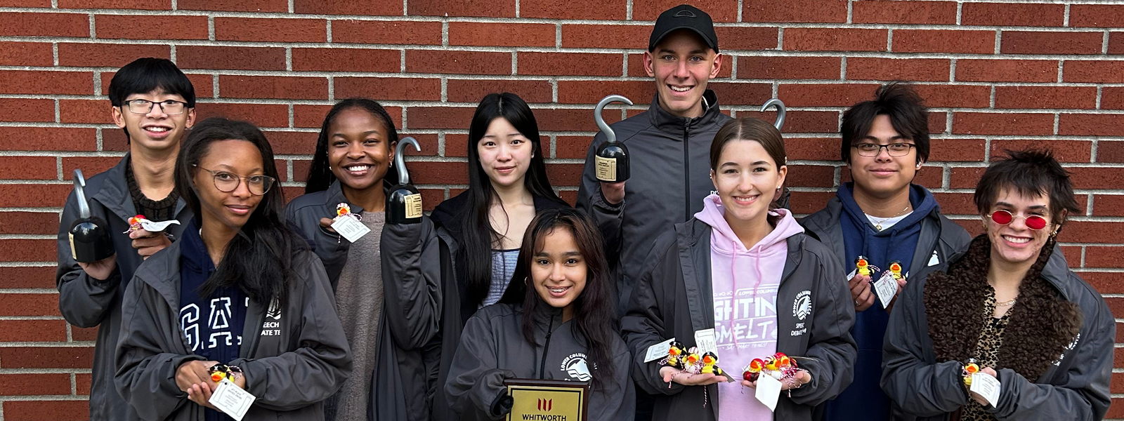 LCC Fighting smelt team standing in front of a brick wall holding their awards