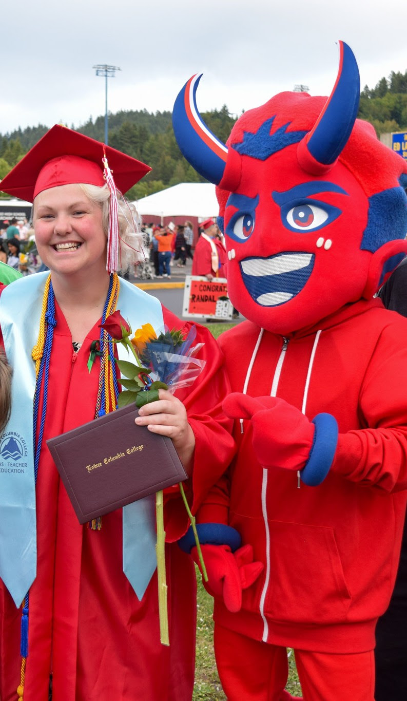 LCC Graduate Juliet wearing red cap and gown holding diploma and flowers, standing nect to LCC mascot Flare, at the LCC Graduation