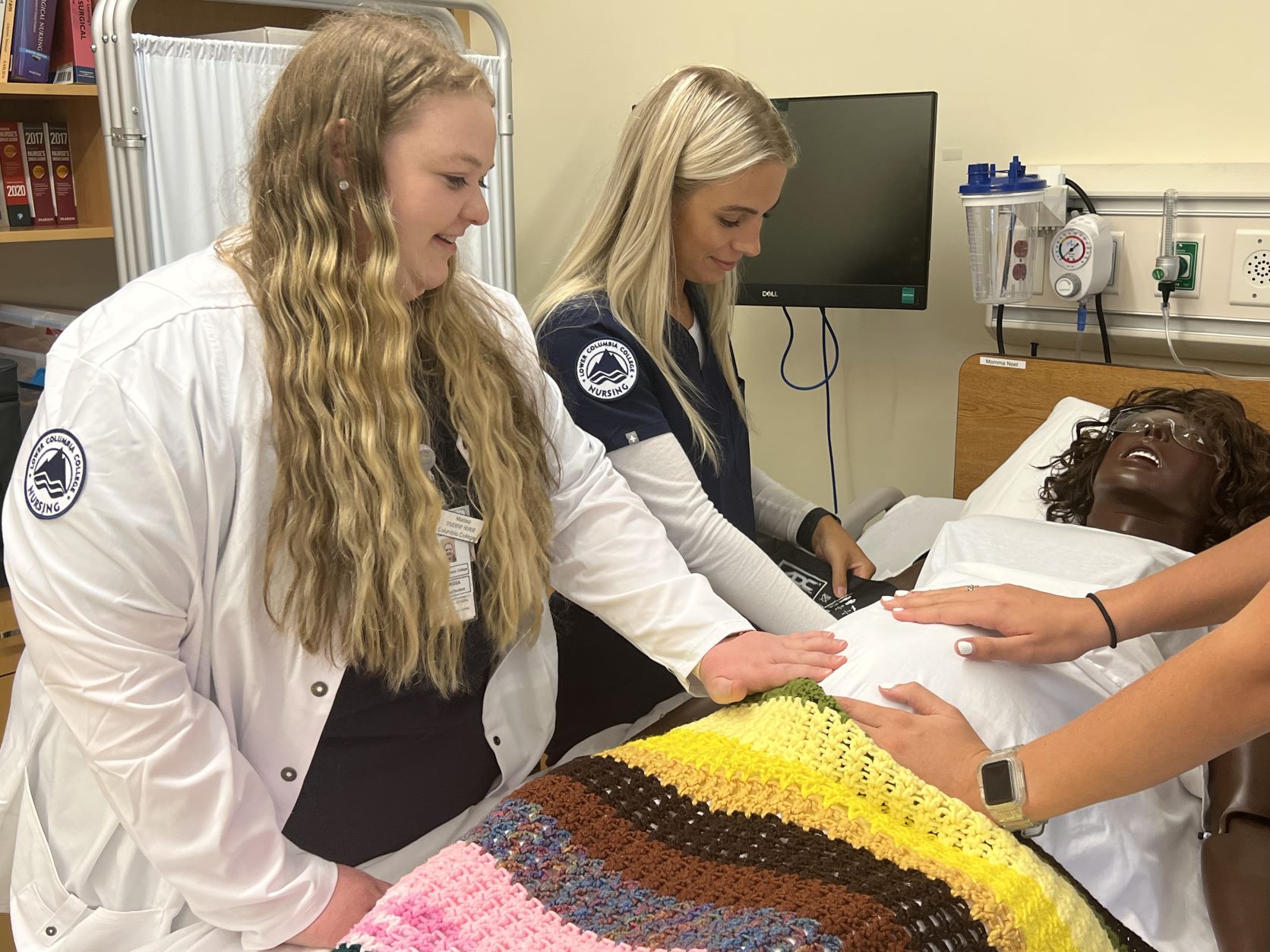 Uniformed nursing students checking manikin's abdomen